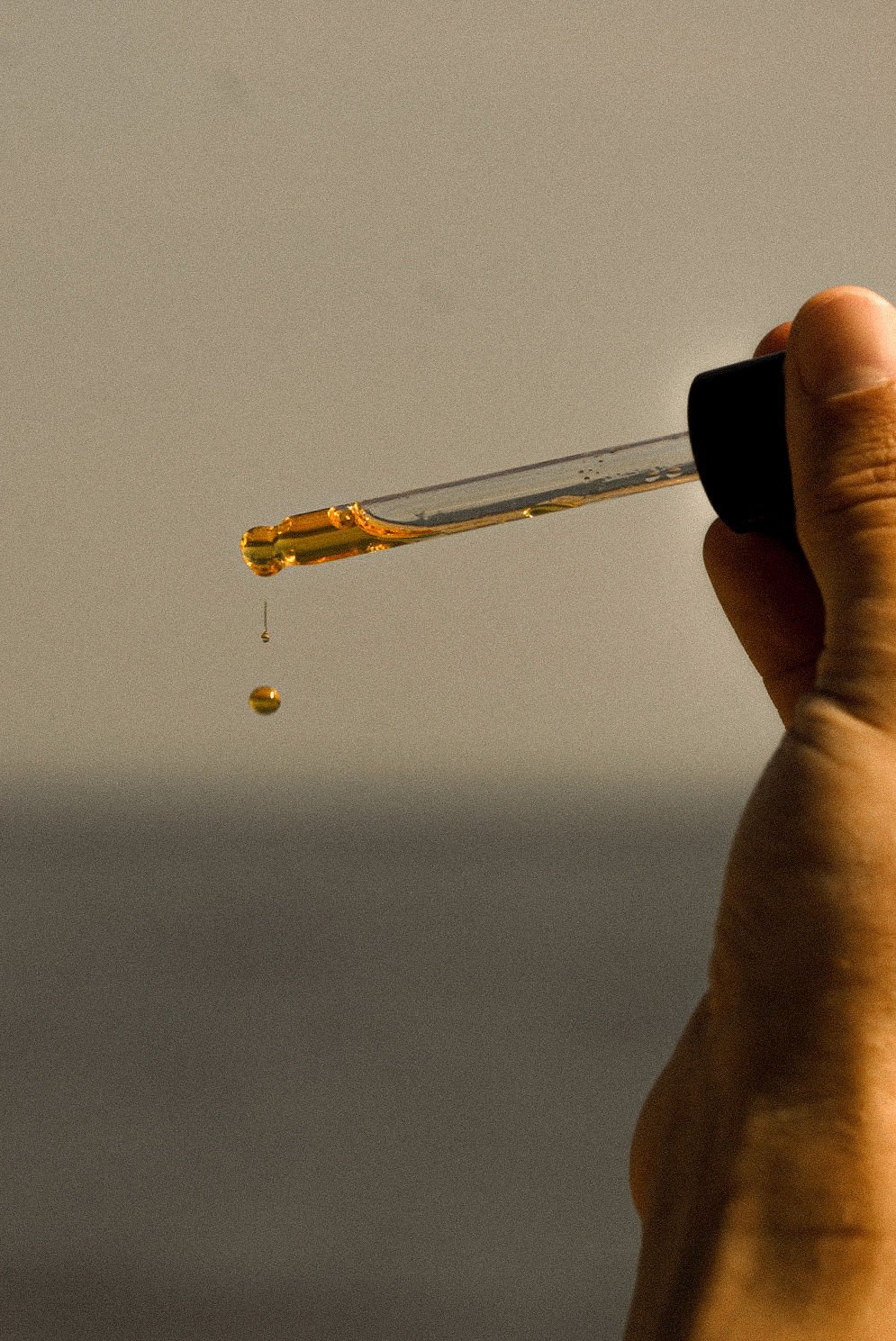 Goldener Serumtropfen an einer Glaspipette – Vaultstock Delicate